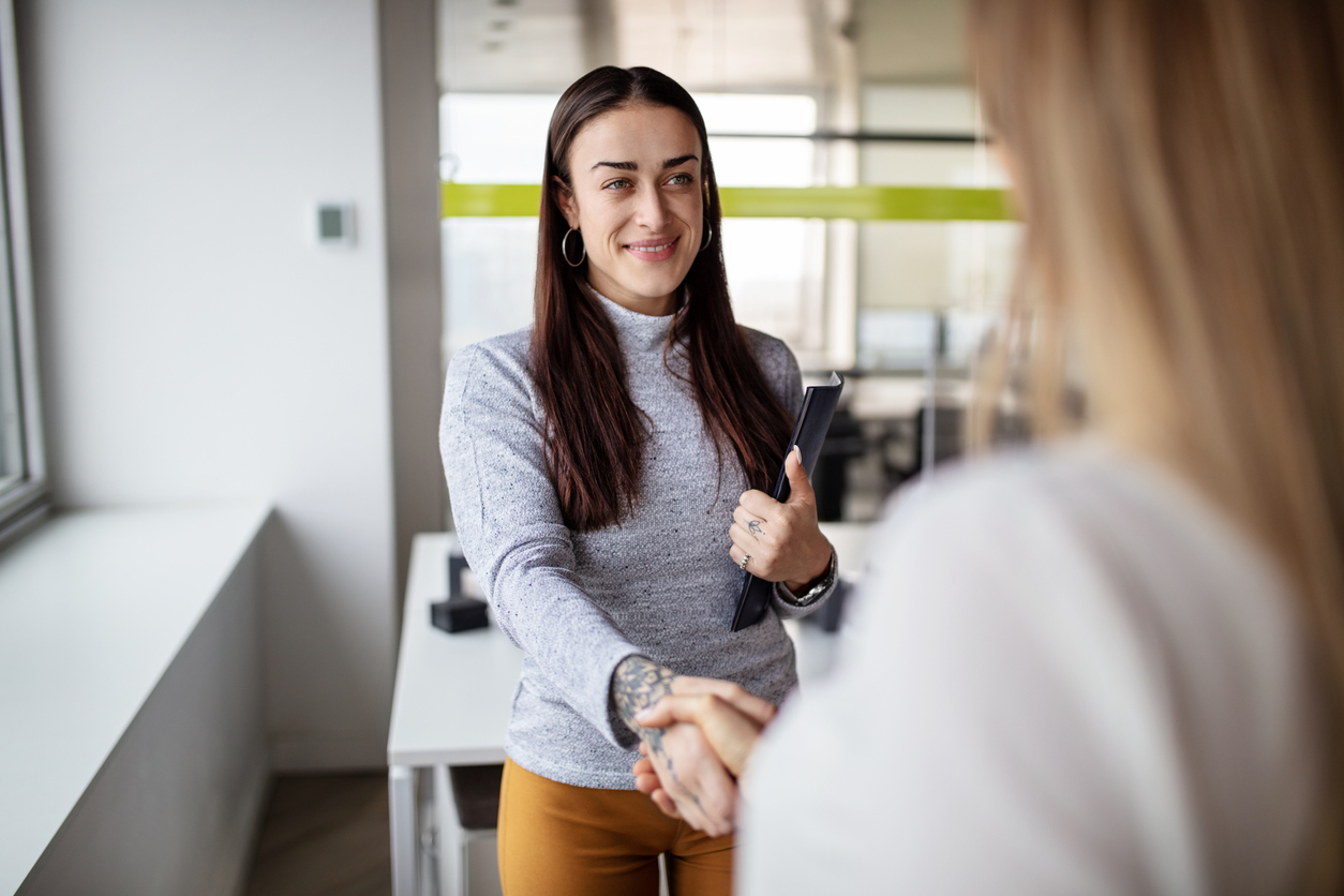 Woman greeting a colleague with handshake in office