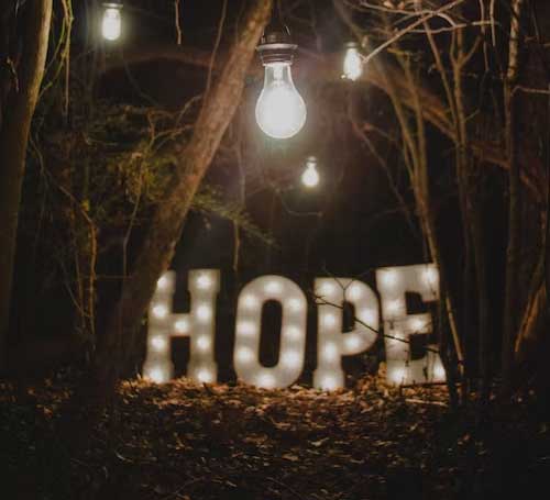 a photo of the word HOPE lighting up a dark forest